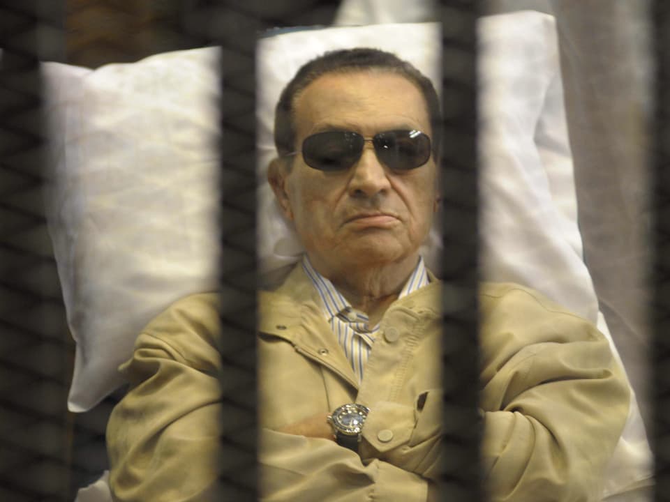 Mubarak hinter Gittern auf einem Bett liegend im Gerichtssaal.
