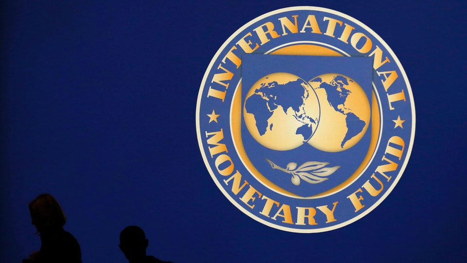 Personen gehen am IWF-Logo vorbei