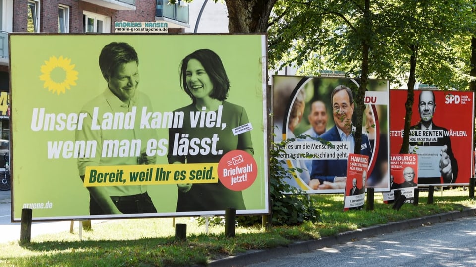 An einem Strassenrand sind Plakate der Kanzlerkandidierenden zu sehen.