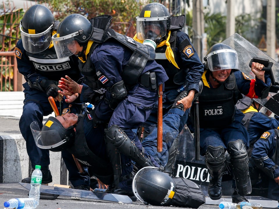 Polizisten tragen einen verwundeten Kollegen weg
