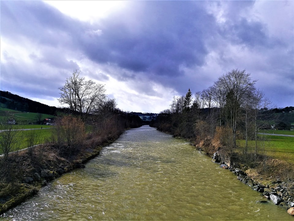 Ein kleiner Fluss, am Ufer  Bäume, der Himmel ist teils mit Wolken überzogen.