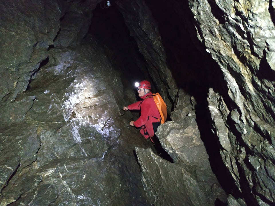 Mann klettert in Höhle.