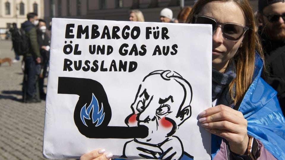Frau mit Plakat: Embargo für Öl und Gas aus Russland.