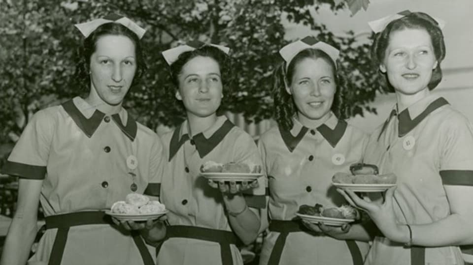 Vier Frauen halten Teller mit Doughnuts in den Händen 