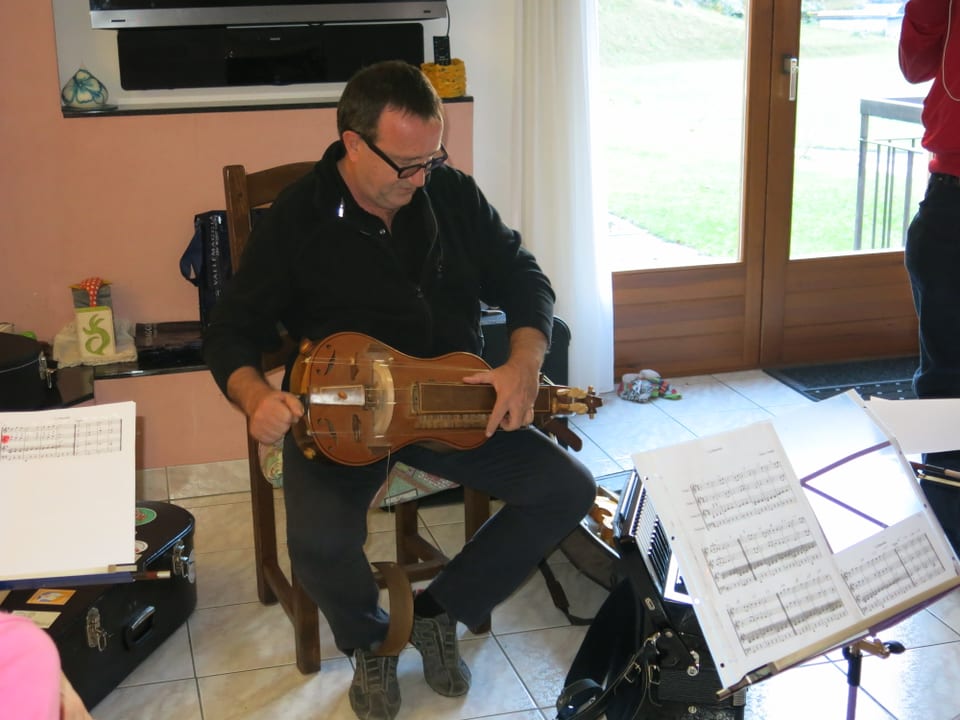Volksmusiker Pietro Bianchi auf einem Stuhl sitzend mit einer Drehleier.