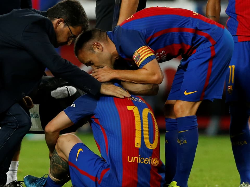 Lionel Messi hauert am Boden und wird umsorgt von seinen Teamkollegen.