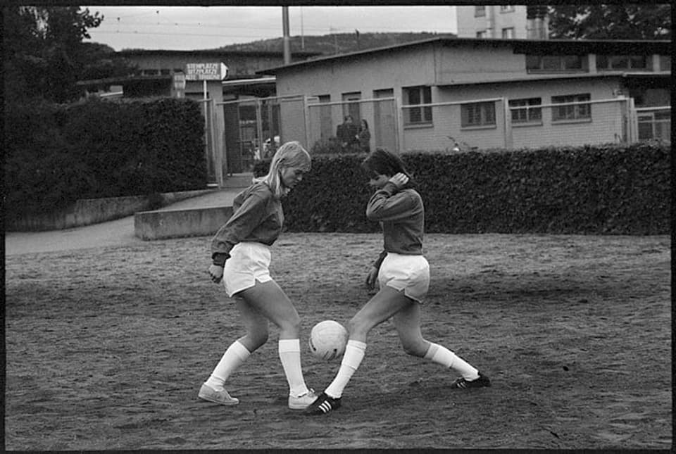 Zwei Frauen spielen auf einem Rasen Fussball.