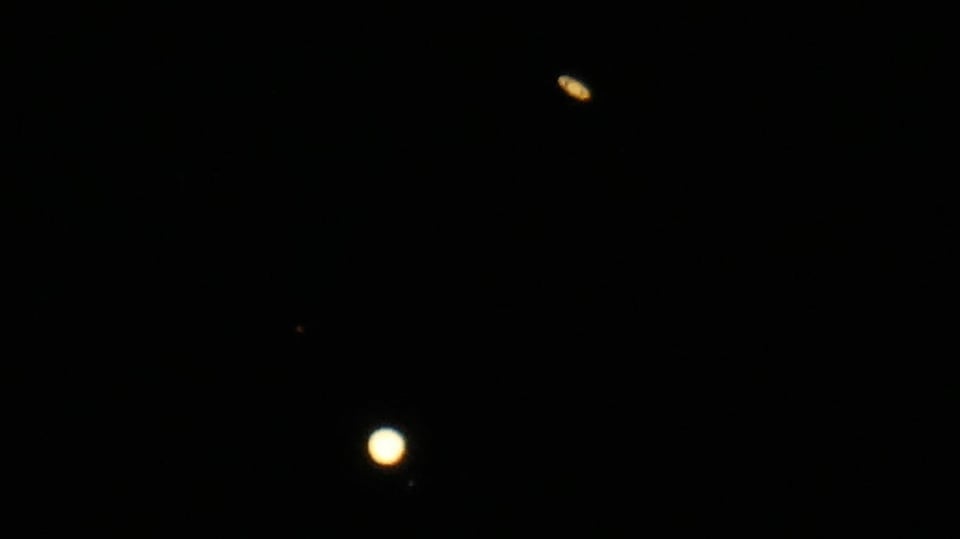 Der kleinere Saturn mit Ringen und der helle, runde Jupiter am schwarzen Himmel