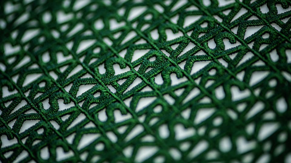 Feine, grüne Stickerei mit dem Schriftzug «Akris».