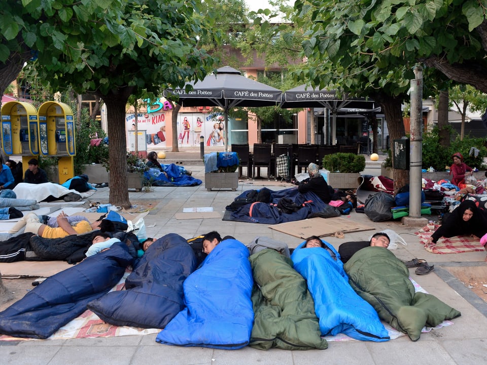 Geflüchtete Männer schlafen in Schlafsäcken auf dem Viktoria-Platz