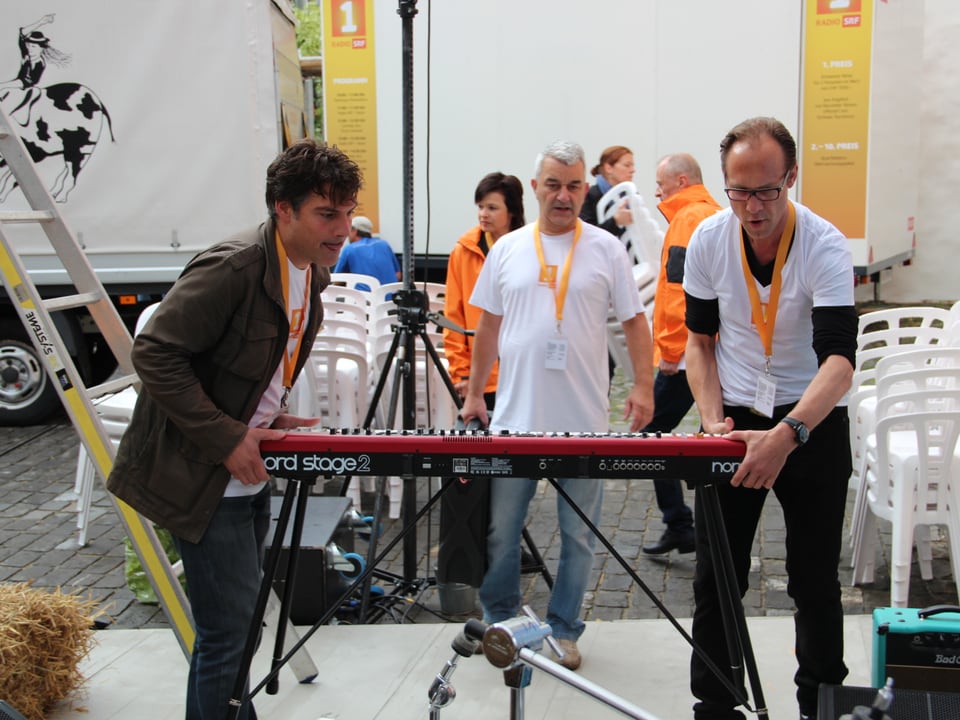 Daniel Schwarz und Christian Zeugin tragen Piano auf die Bühne.