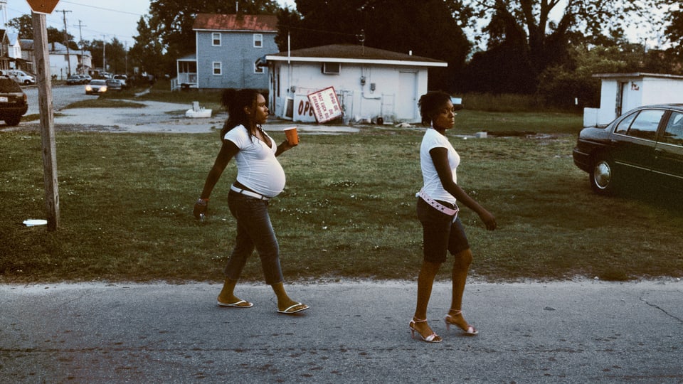 Foto einer Strasse in New Bern. Von links nach recht laufen zwei schwarze Frauen durchs Bild, eine mit Babybauch.