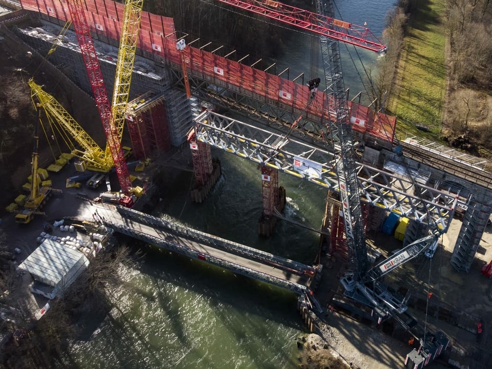 Ein Kran hat die neue, 340 Tonnen schwere Stahlbrücke des Bahnviadukts über die Saane bei Gümmenen BE auf ein 20 Meter hohes Gerüst gehoben.
