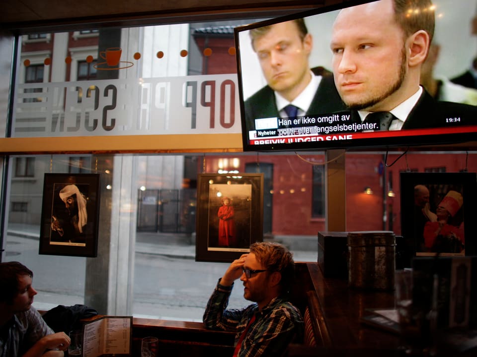 Restaurant in Oslo. Am TV läuft Berichterstattung über Breivik.