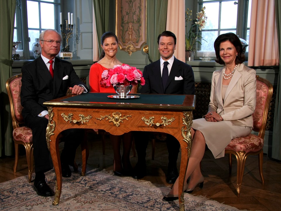 König Carl Gustaf, Prinzessin Victoria, Prinz Daniel und Königin Silvia an einem Tisch sitzend.