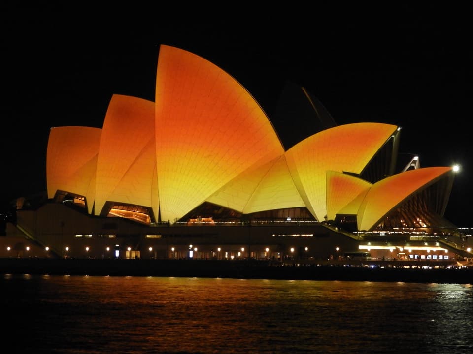 Opernhaus von Sydney mit orange und gelb beleuchtet. 