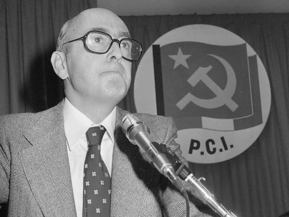 Napolitano an einem Rednerpult, im Hintergrund das Symbol der kommunistischen Partei P.C.I.