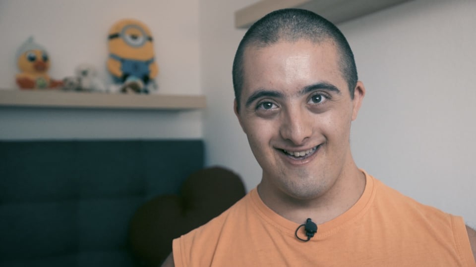 Noha ist Schauspieler und hat Trisomie 21. Noha lächelt in die Kamera.