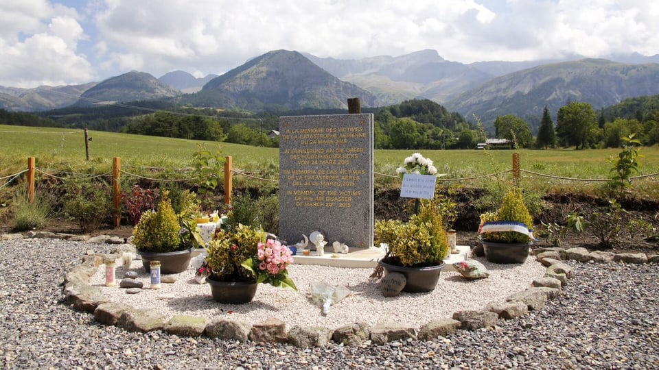 Ein Gedenkstein mit Blumen und Kerzen geschmückt. 
