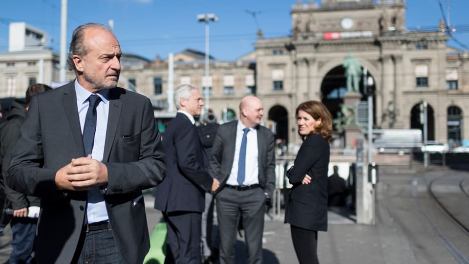 Filippo Leutenegger schaut streng, dahinter bürgerliche Politiker vor dem Hauptbahnhof
