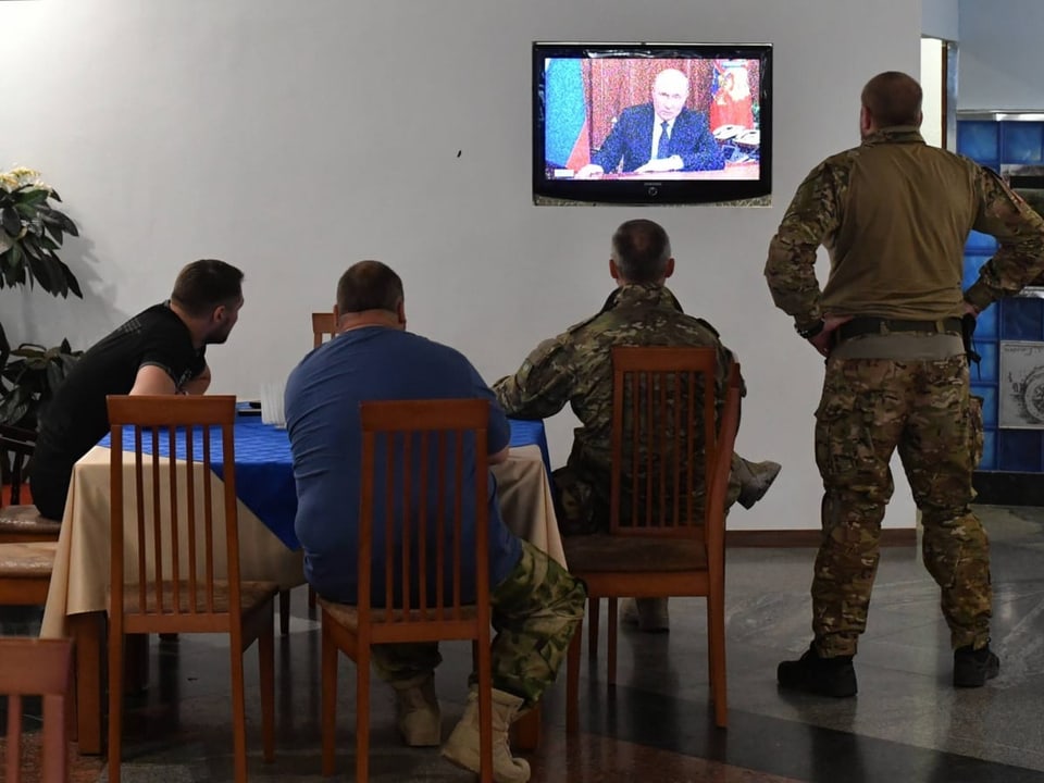 Soldaten in der Volksrepublik Donezk schauen im Fernsehen die Rede von Putin an die Nation.