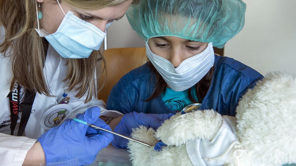 Kind und Spitalangestellte operieren zusammen einen Teddybär.
