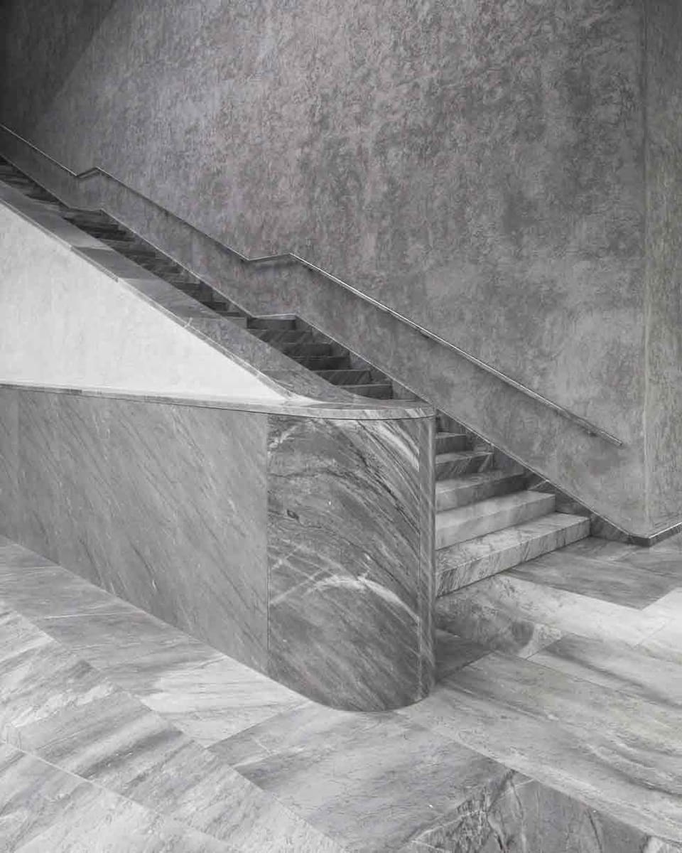 Ein Treppenhaus: Stufen und Boden aus Marmor, Wände aus Beton.