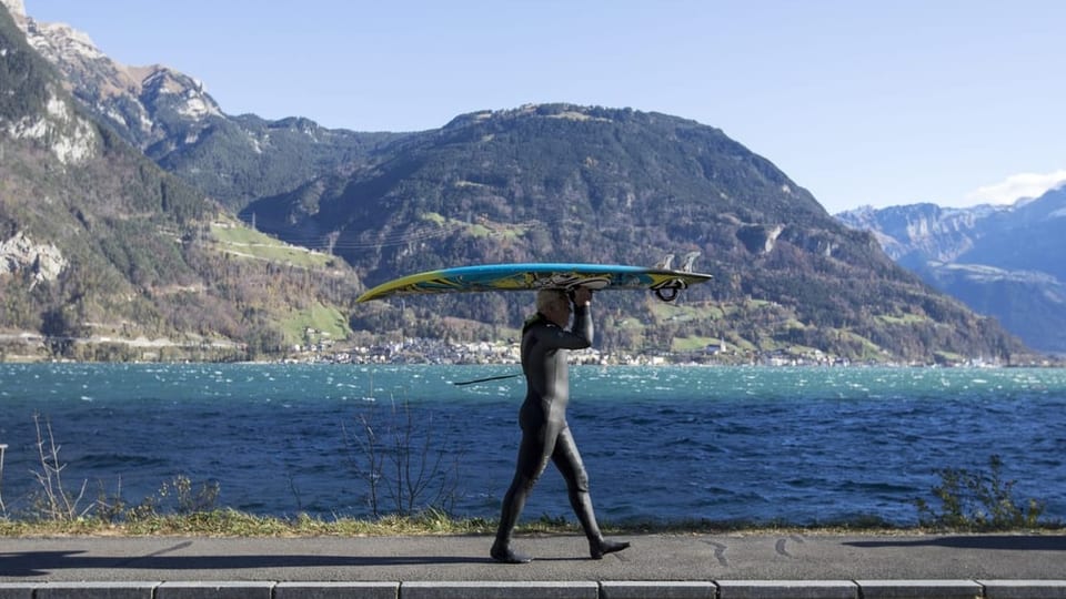 Mann trägt sein Surfbrett zum Ufer.