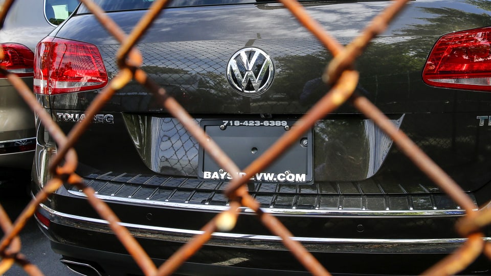VW-Modell hinter einem rostigen Maschendrahtzaun.