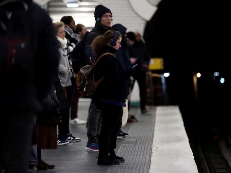 Passagiere stehen auf einem Bahnsteig der Metrostation Saint-Lazare