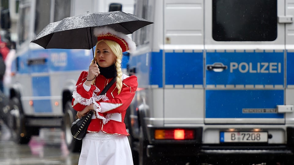 Ein Frau in Karnevalstracht vor einem Polizeibus. 