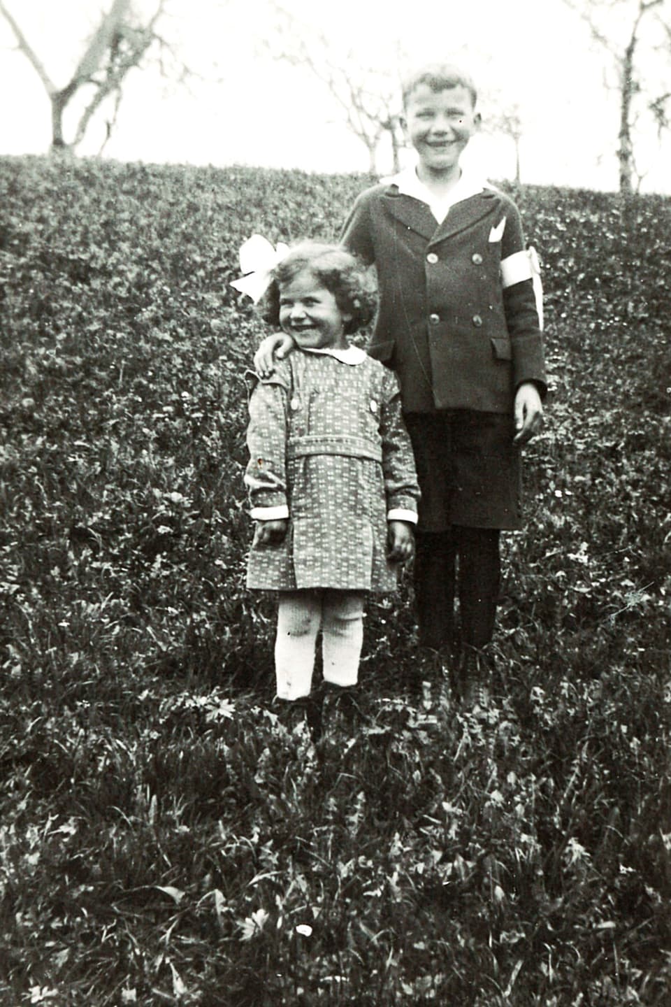 Zwei lächelnde Kinder auf einer Wiese (schwarzweissfoto).