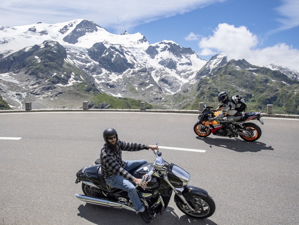 Zwei Motorräder kreuzen sich auf eine Passstrasse in den Alpen.