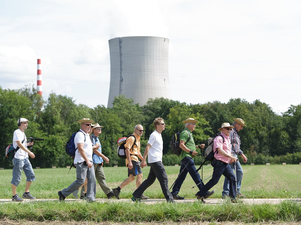 Wandergruppe auf einem Feldweg, im Hintergrund der Kühlturm des Kernkraftwerks Gösgen.