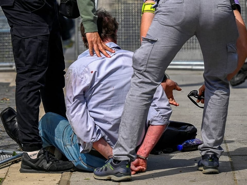 Polizisten verhaften eine Person auf dem Boden.