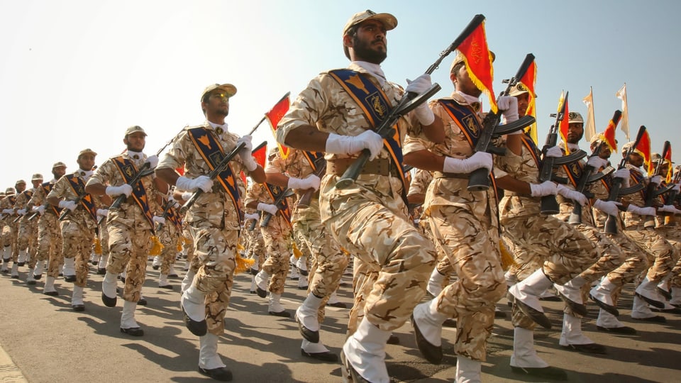 Soldaten in sandfarbenen Kampfanzügen marschieren.