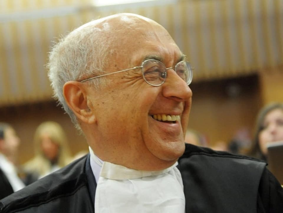 Man in lawyer's robe smiles at camera