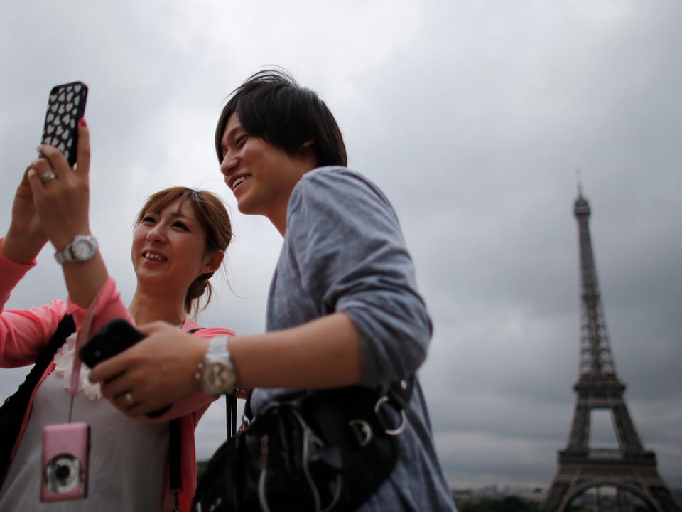 Japanische Touristen vor dem Eiffelturm in Paris.