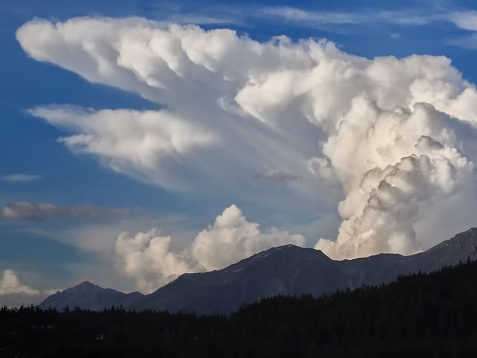 Gewitterwolke am blauen Himmel, die sich weit hoch türmt. 