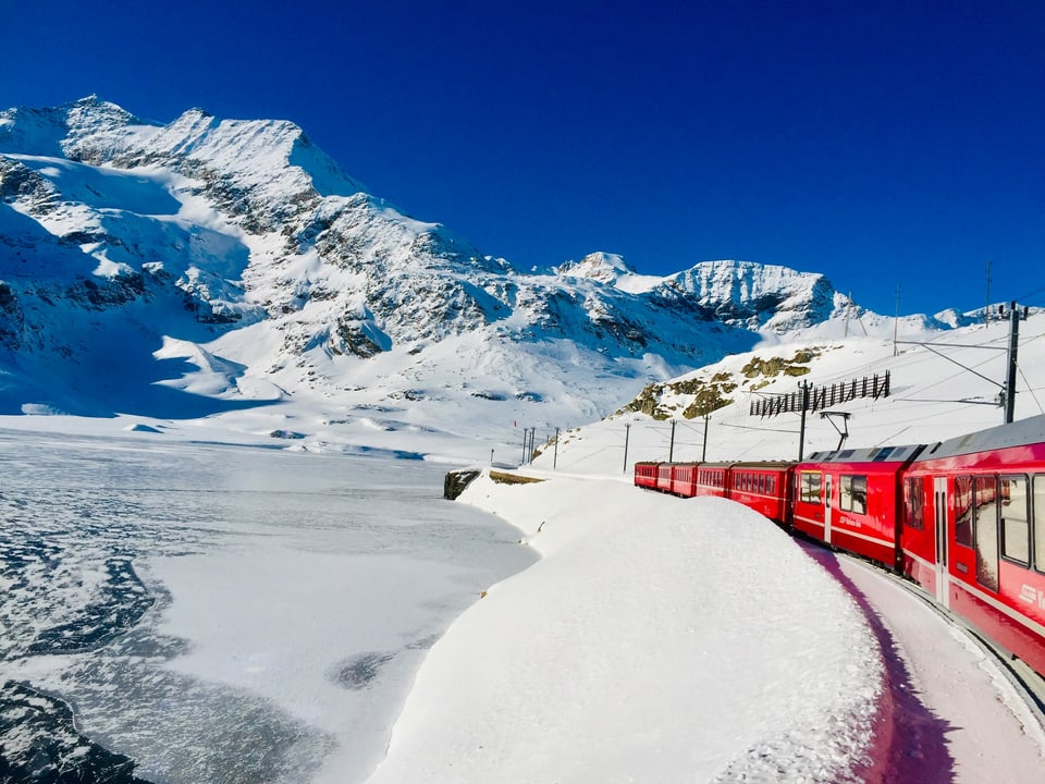 Roter Zug fährt durch Schneelandschaft.