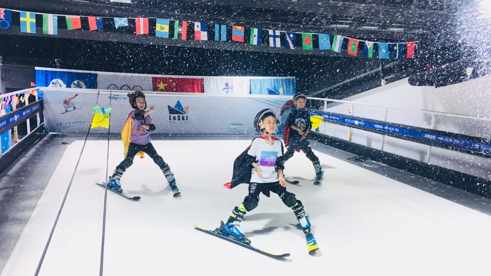 Chinesische Kinder fahren in einer Indoor-Skihalle