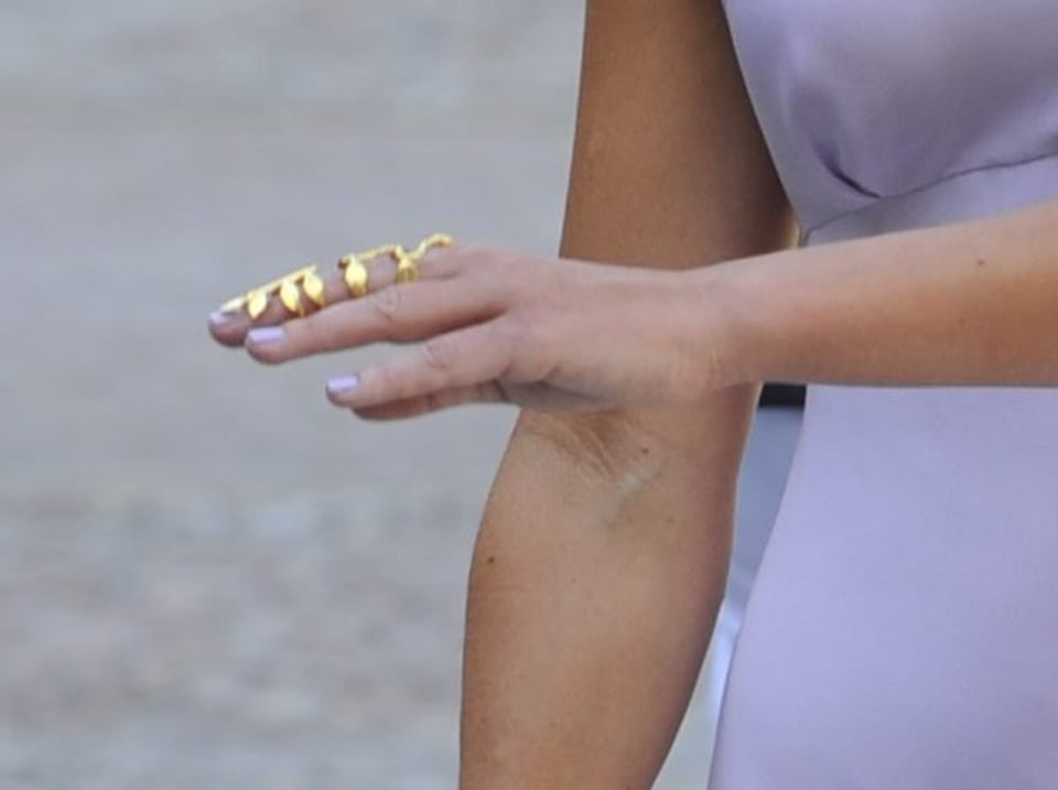Eine Hand mit einem goldenen Fingerring, der an einen kleinen Ast erinnert und fast den ganzen Finger bedeckt.