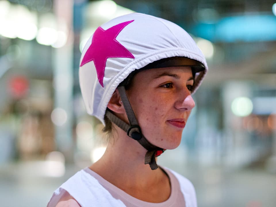 Frau mit Helmüberzug, der mit einem rosa Stern versehen ist. 