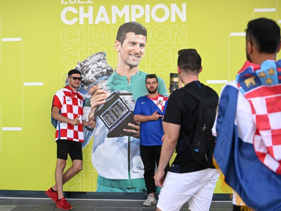 Fans posieren vor einem Djokovic-Plakat in Melbourne.