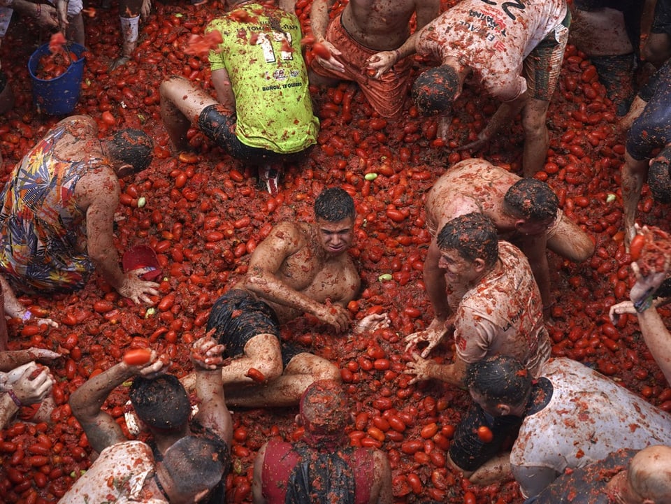 Menschen liegen in Massen von Tomaten