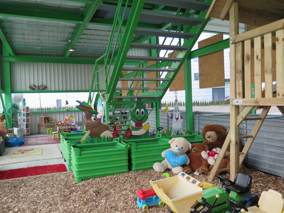 Grüne Treppe, grüne Boxen, diverse Spielsachen und Holzhäuschen.