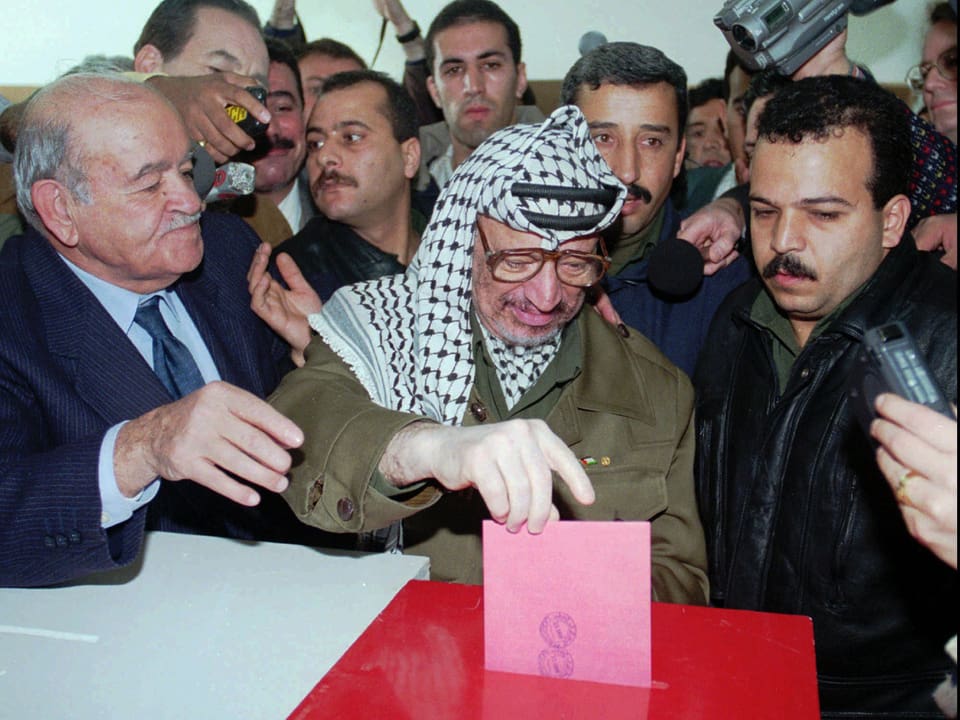 Arafat gibt seinen Wahlzettel in eine Urne