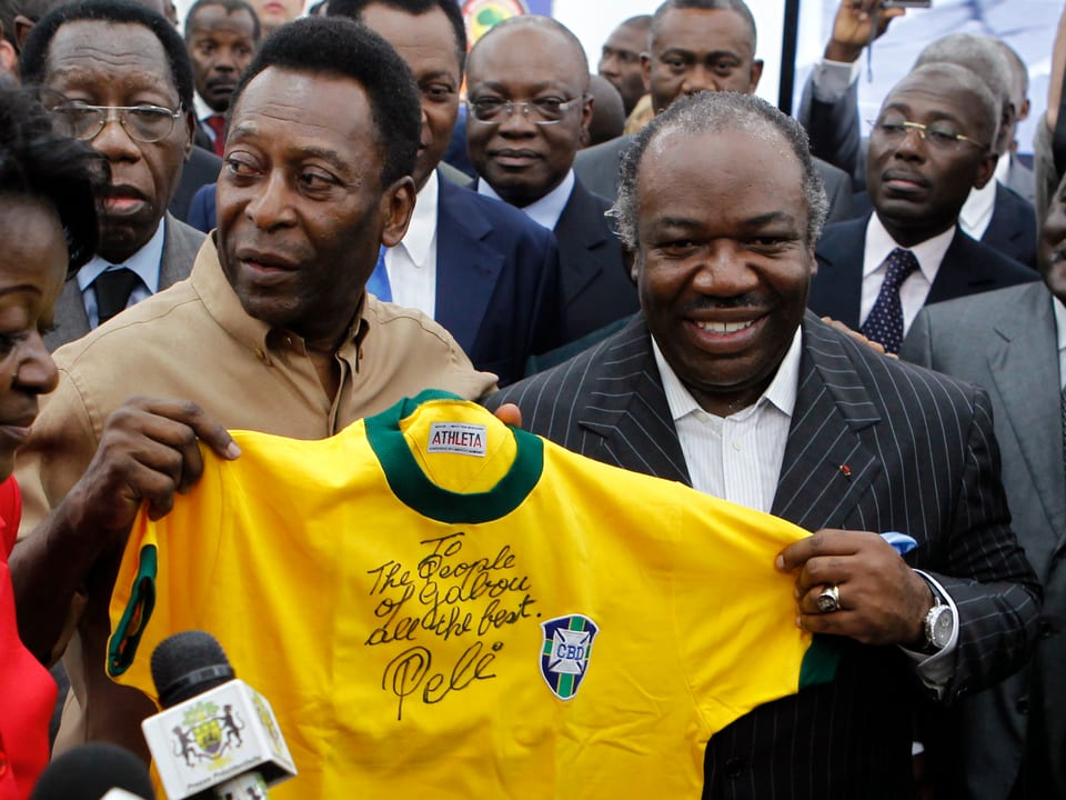 Pele und Bongo Ondimba ein T-Shirt haltend.