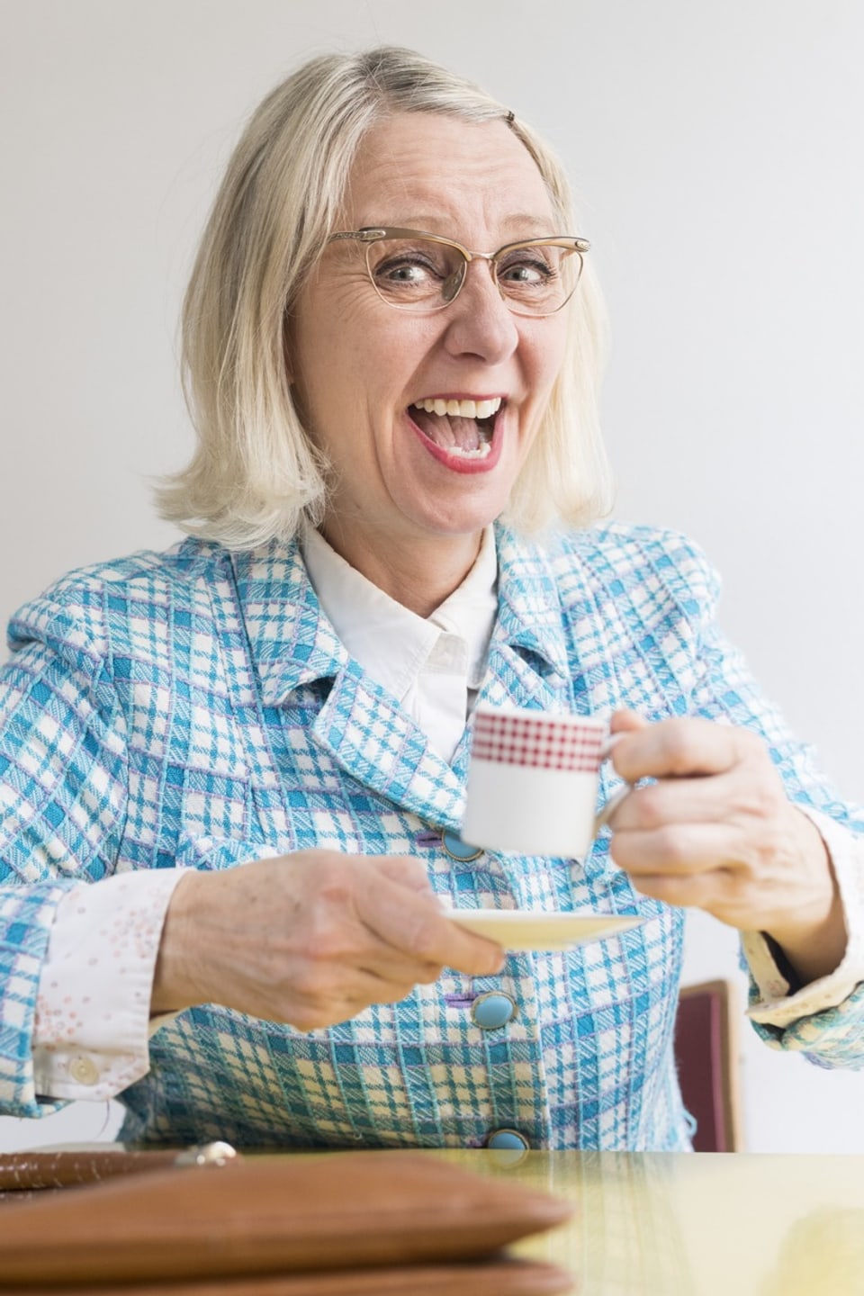 Barbara Hutzenlaub sitz an einem Tisch und hält eine Kaffeetasse in der Hand. 