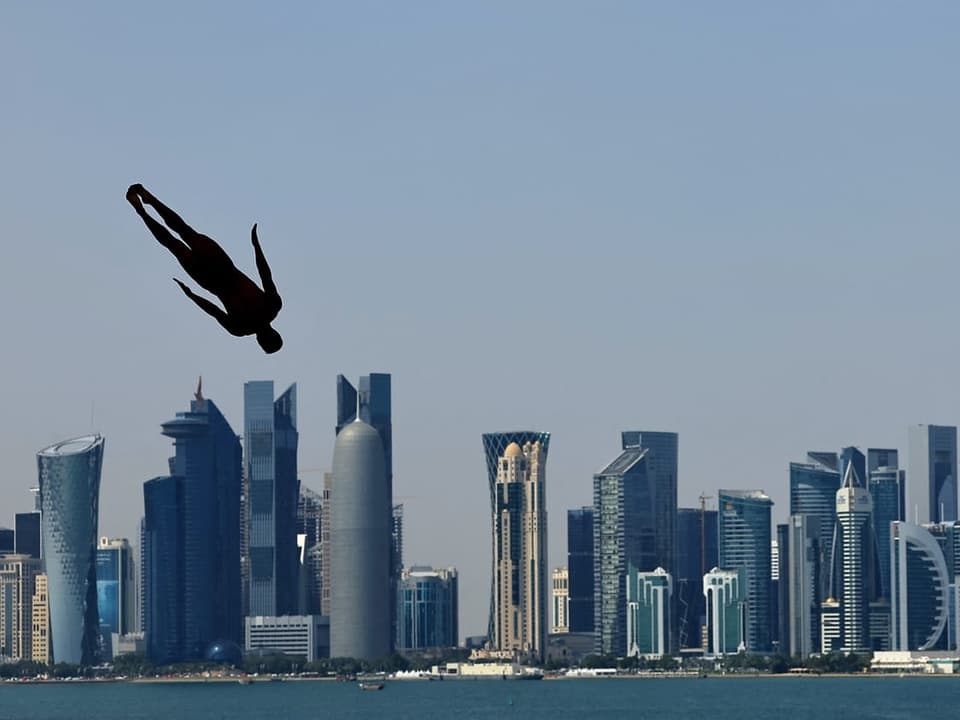Ein Mann scheint über die Stadt Doha zu fliegen, während er von einem Turm springt.
